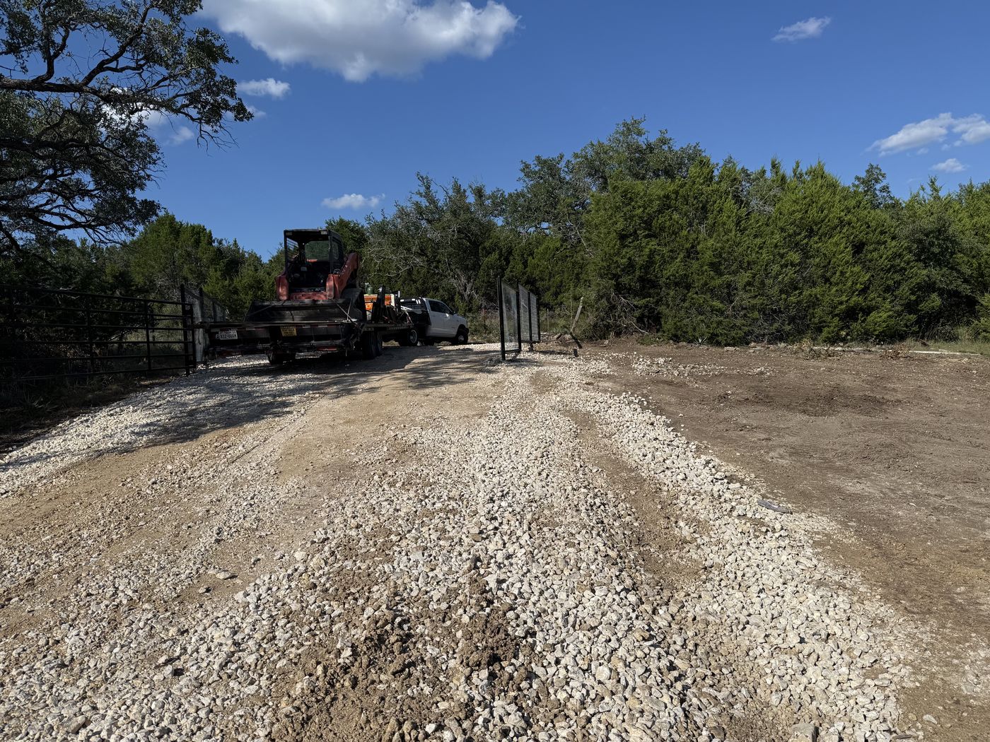 Truck, trailer, and skid steer on a dirt job